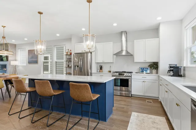 a kitchen with stainless steel appliances granite countertop a stove a sink island and a wooden floor