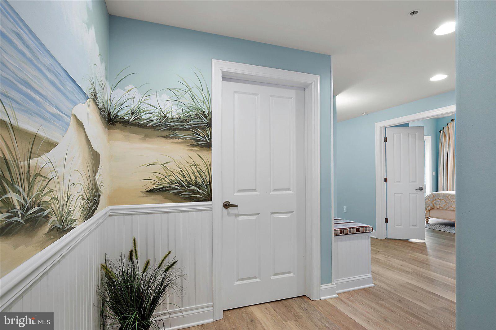 121 81st Street, Unit 907 Ocean City, MD 21842 - Photo 28 of 73 a view of a hallway to a livingroom with wooden floor and a potted plant