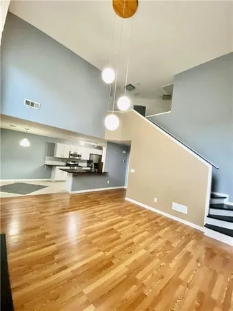 a view of kitchen and empty room with wooden floor