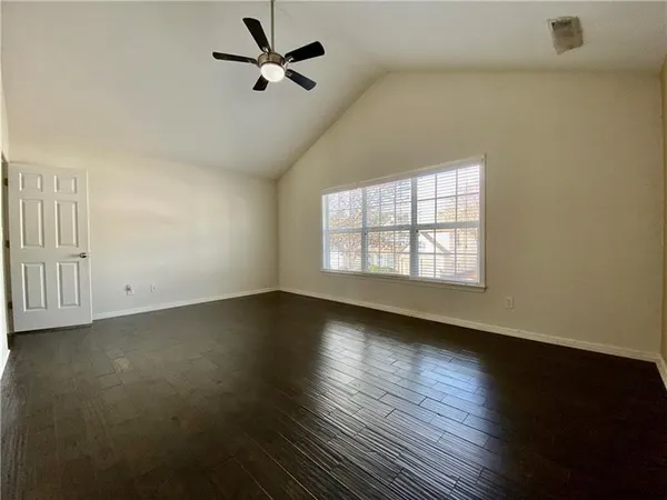an empty room with wooden floor fan and windows