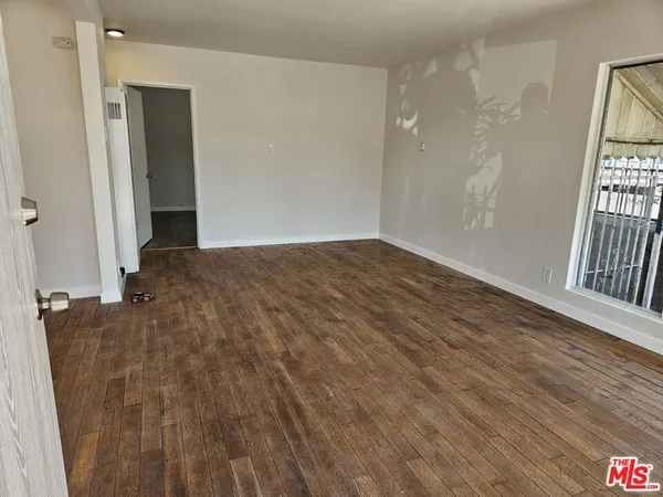 a view of an empty room with wooden floor and a window