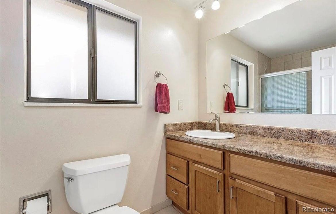 13134 Peacock Drive Lone Tree, CO 80124 - Photo 7 of 11 a bathroom with a granite countertop sink a toilet and a mirror