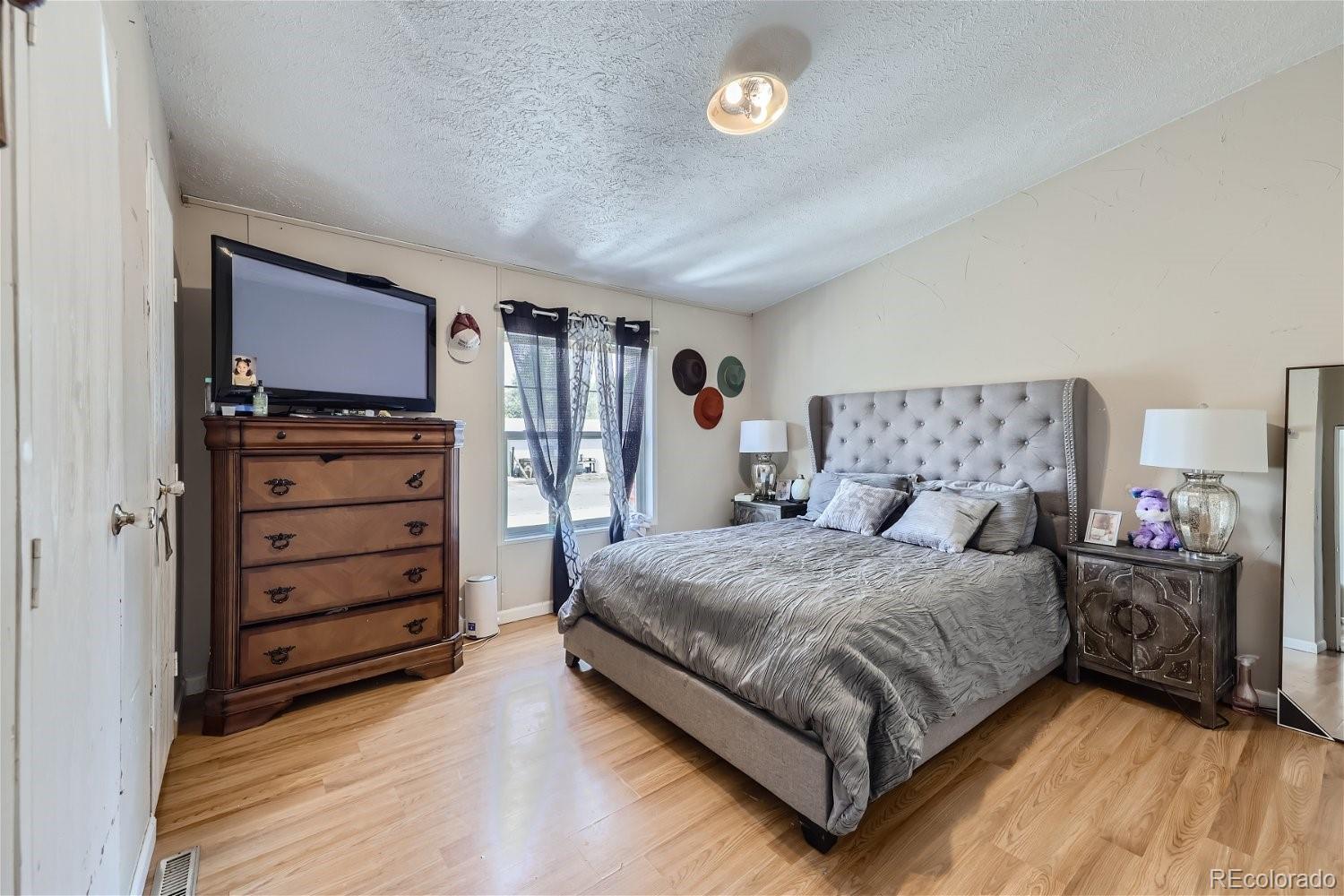 11682 Frederick Street Fort Lupton, CO 80621 - Photo 8 of 11 a bedroom with a bed and a dresser