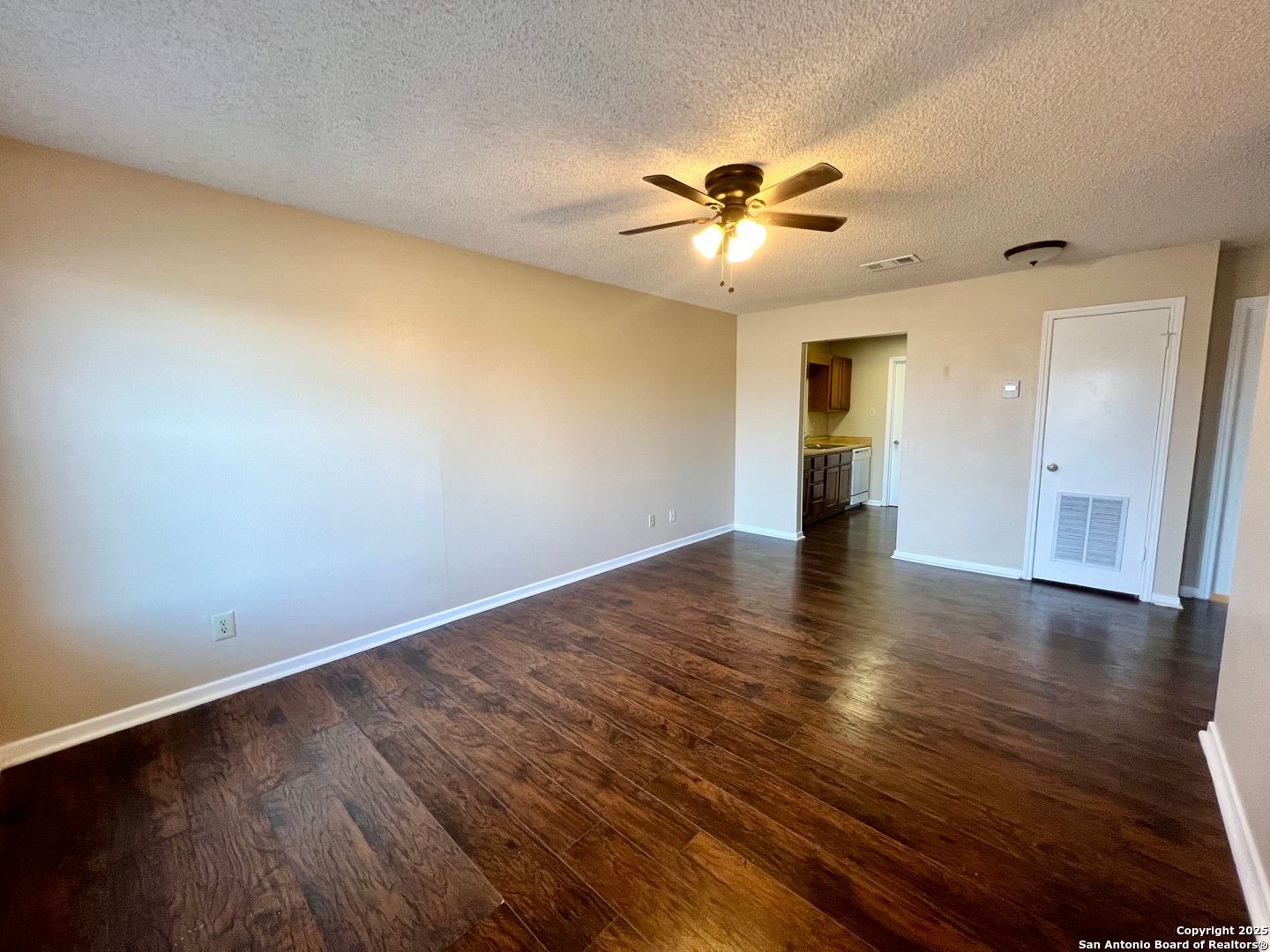 4545 Hoeneke Drive, Unit 103 Kirby, TX 78219 - Photo 4 of 19 a view of an empty room with wooden floor and a ceiling fan