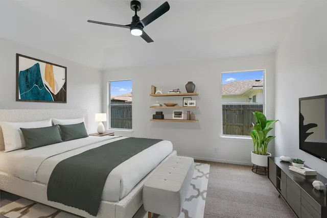 a bedroom with a bed a computer on the desk and a potted plant