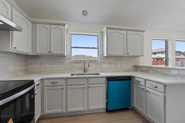 a kitchen with white cabinets sink and appliances