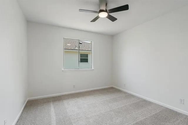 an empty room with a window and ceiling fan