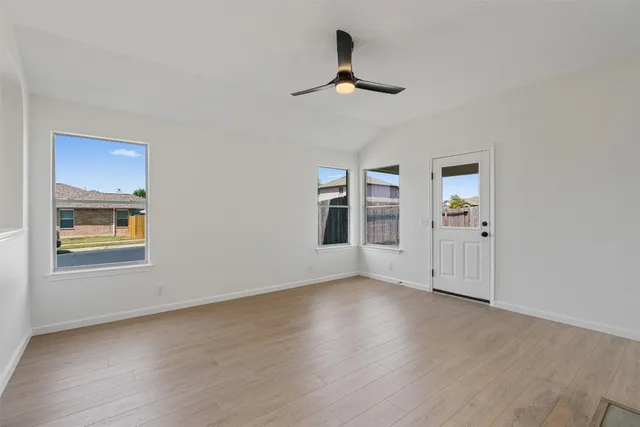 a view of an empty room with a window and wooden floor
