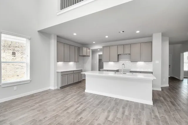 an empty room with wooden floor chandelier fan and windows