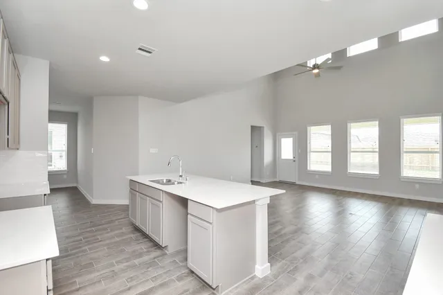 a view of a kitchen with kitchen island stainless steel appliances wooden floor and view living room
