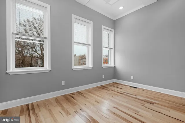 a view of empty room with wooden floor and fan