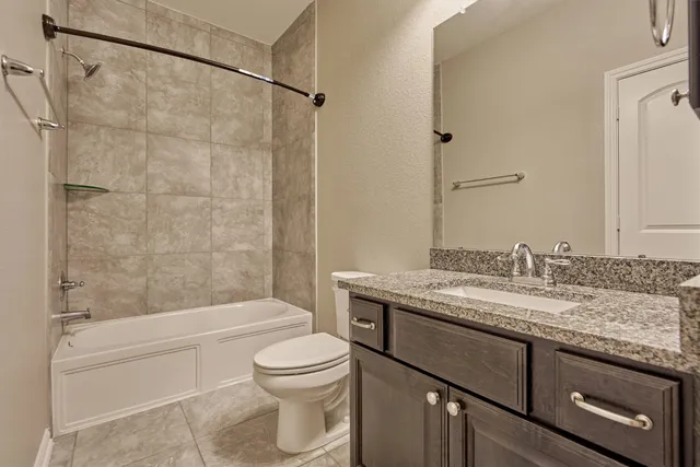 a bathroom with a granite countertop bathtub shower sink vanity and toilet