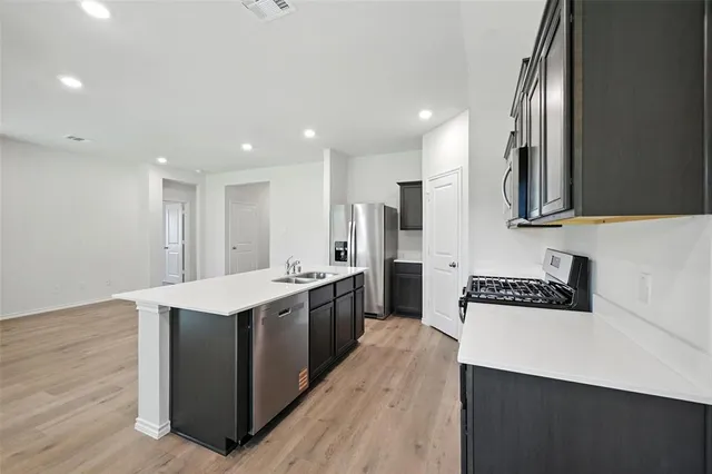 a view of kitchen with kitchen island wooden floor center island and stainless steel appliances
