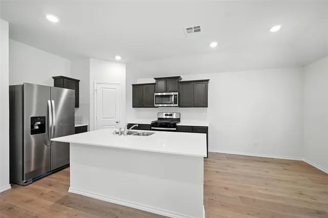 a view of kitchen with microwave oven on refrigerator and white cabinets