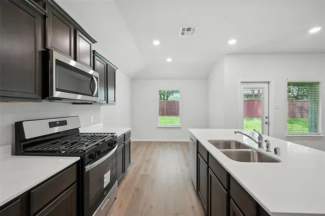 a kitchen with stainless steel appliances a refrigerator stove microwave and sink