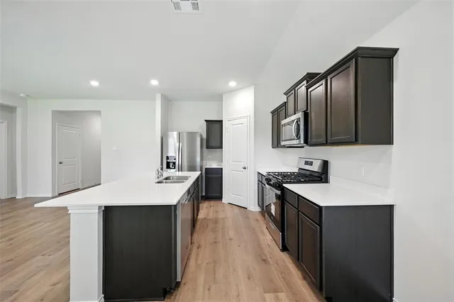 a kitchen with a refrigerator a stove top oven a sink dishwasher and wooden floor