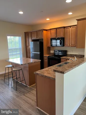 a kitchen with stainless steel appliances a microwave a stove a sink a refrigerator and chairs