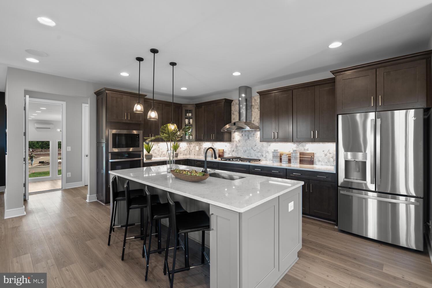 a kitchen with stainless steel appliances a table chairs refrigerator and wooden floor