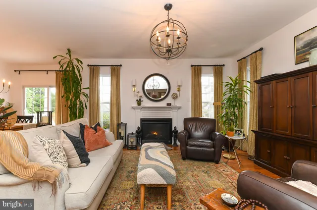 a living room with furniture a chandelier a fireplace and a window