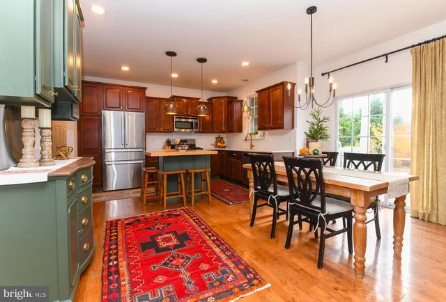 a dining hall with stainless steel appliances granite countertop a dining table and chairs with the wooden floor