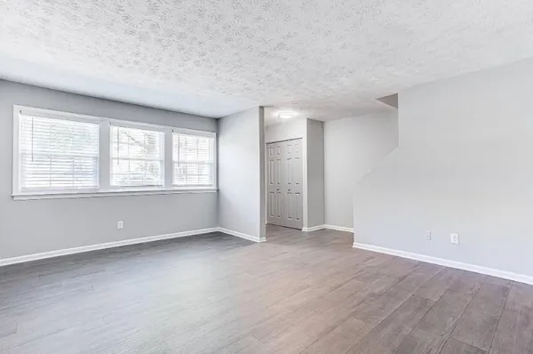 an empty room with wooden floor and windows