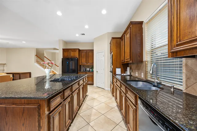 a large open kitchen with stainless steel appliances kitchen island granite countertop a refrigerator and cabinets