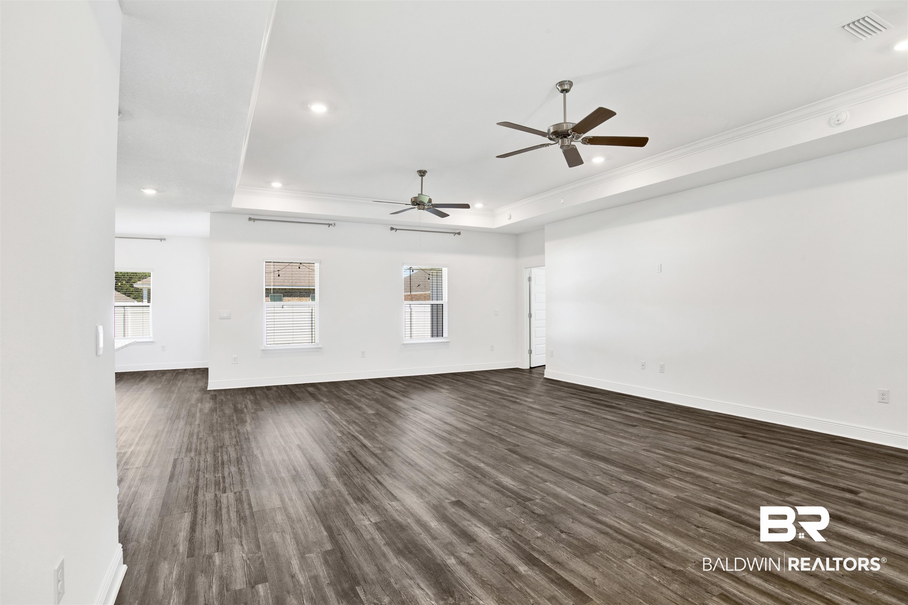 11602 Genuine Risk Circle Daphne, AL 36526 - Photo 5 of 30 Unfurnished living room featuring dark wood-style flooring, a raised ceiling, recessed lighting, ornamental molding, and ceiling fan