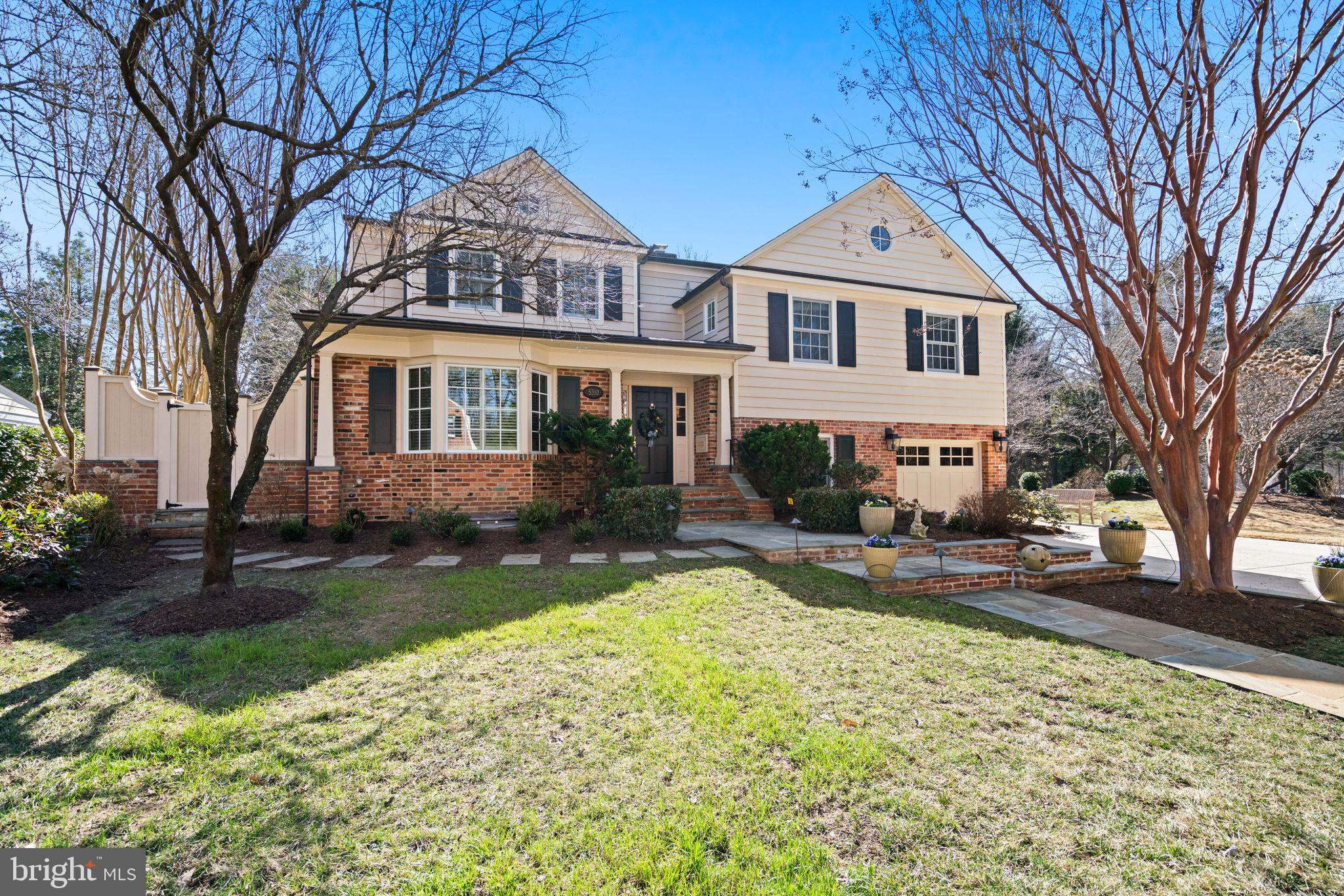 a front view of a house with garden and trees