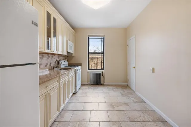 a kitchen with granite countertop a stove a sink and a refrigerator