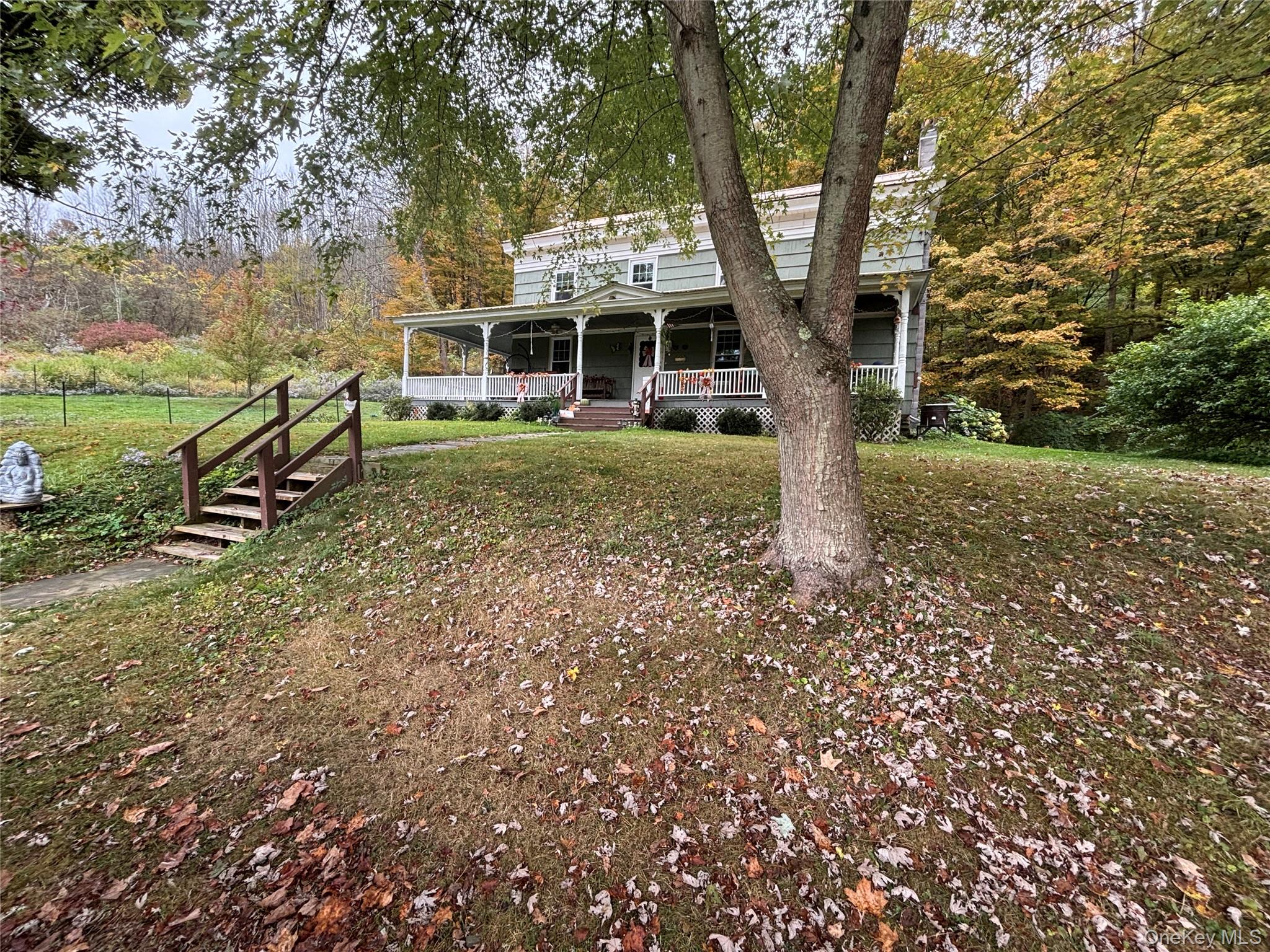 View of front of house with a large porch, a front lawn, and a chimney