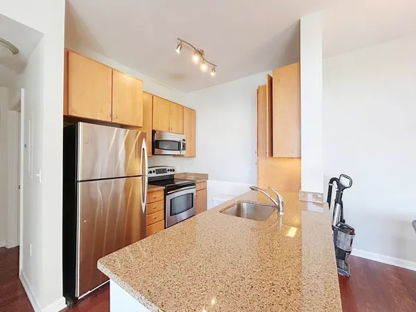a kitchen with granite countertop a refrigerator a stove a sink a washer and dryer