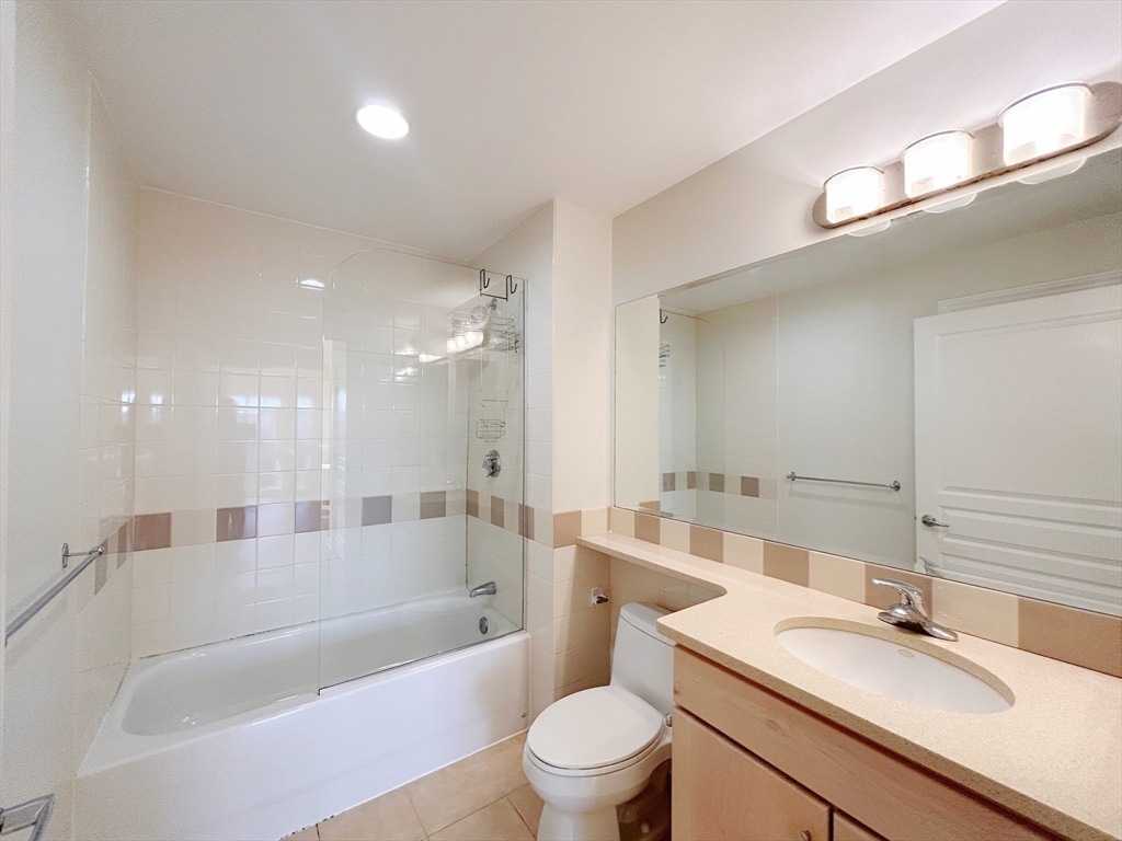 4 Repton Place, Unit 4415 Watertown, MA 02472 - Photo 14 of 25 a bathroom with a bathtub shower sink vanity mirror and toilet