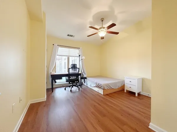 a spacious bedroom with a bed and wooden floor