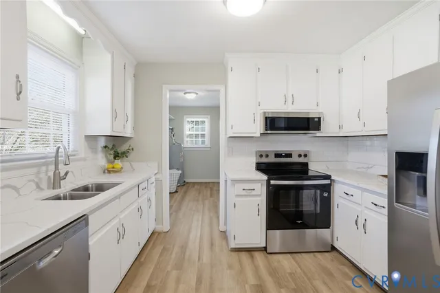 a kitchen with stainless steel appliances white cabinets a sink a stove a refrigerator and microwave