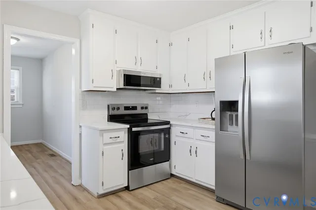 a kitchen with stainless steel appliances a refrigerator stove and white cabinets