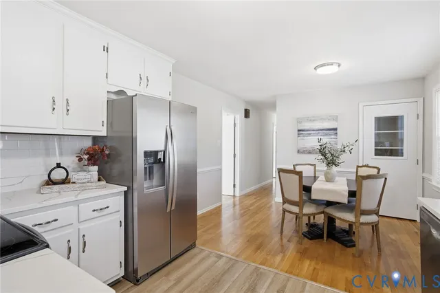 a kitchen with stainless steel appliances kitchen island granite countertop a dining table chairs and a refrigerator