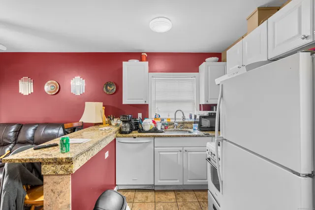 a white kitchen with a sink a refrigerator and a stove