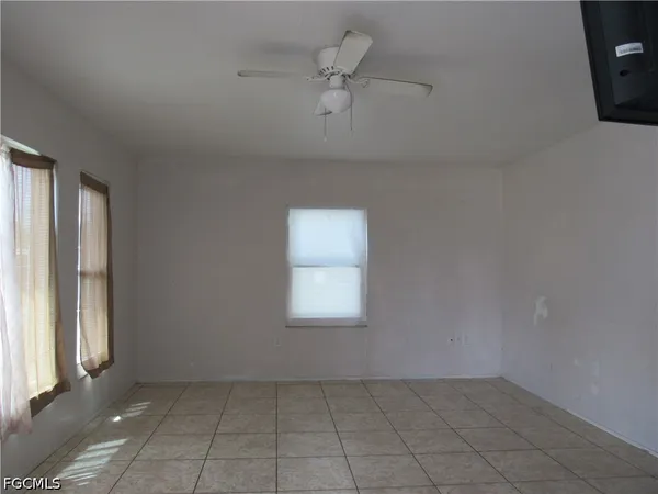 an empty room with a window and a ceiling fan