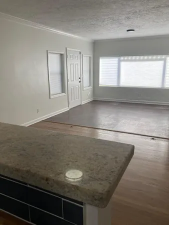 a view of kitchen and empty room with wooden floor
