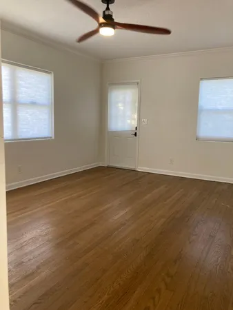 a view of an empty room with wooden floor and a window