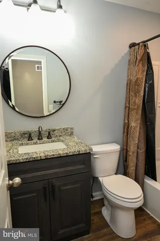 a bathroom with a granite countertop toilet sink and mirror