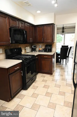 a kitchen with stainless steel appliances a stove a sink a microwave a dining table and chairs