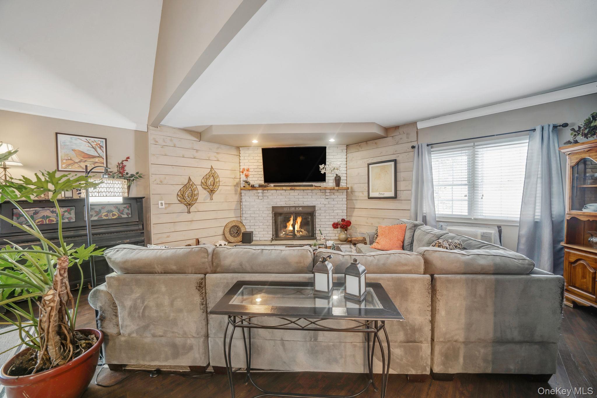 6 Howe Court Coram, NY 11727 - Photo 3 of 17 a living room with furniture a flat screen tv and a fireplace