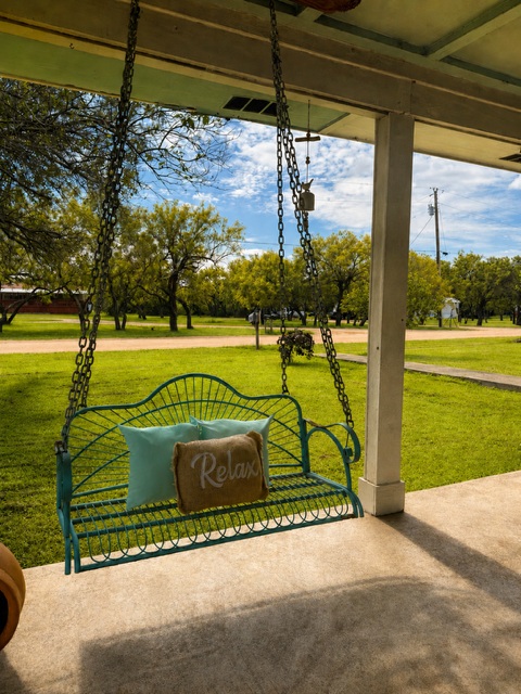 221 Winding Way Road Marble Falls, TX 78654 - Photo 18 of 19 A tranquil porch swing invites relaxation with verdant grounds stretching into the distance with beautiful trees.