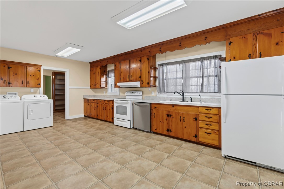 5633 Wilson Creek Road Virginia Beach, VA 23464 - Photo 8 of 44 Kitchen featuring white appliances, under cabinet range hood, a sink, washer and dryer, and brown cabinets