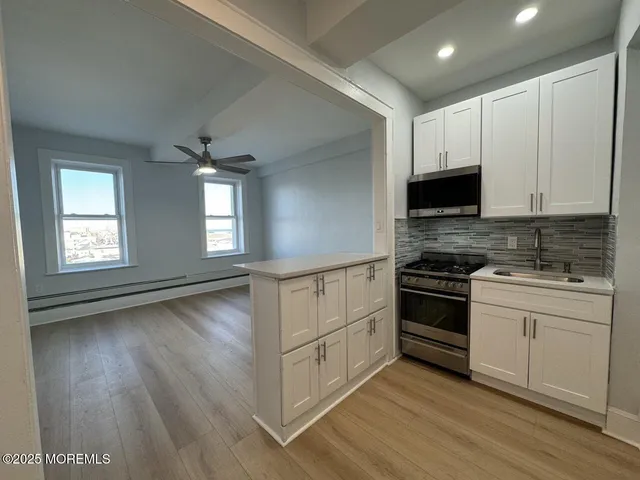 a kitchen with stainless steel appliances white cabinets and wooden floor