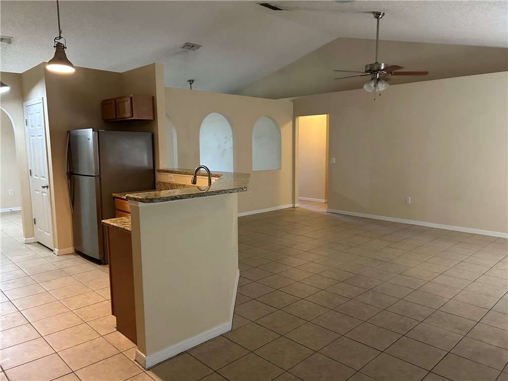 675 Forster Avenue Sebastian, FL 32958 - Photo 6 of 15 a kitchen with kitchen island a granite counter top and a refrigerator