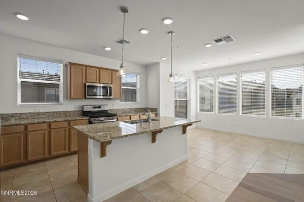 a kitchen with stainless steel appliances granite countertop a stove top oven a sink dishwasher a refrigerator and white cabinets with wooden floor