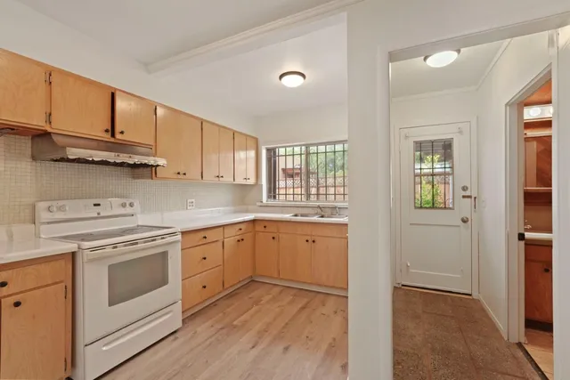 a kitchen with cabinets stainless steel appliances and wooden floor