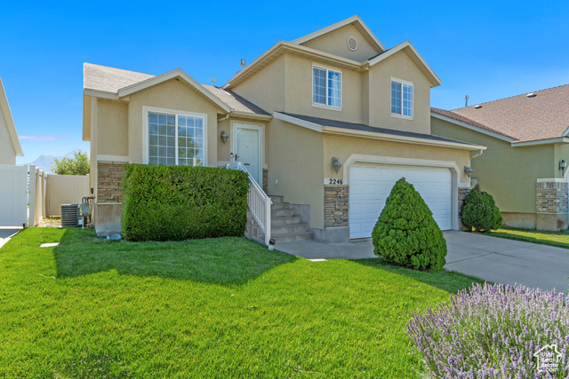 View of front facade with a garage, central AC, and a front yard